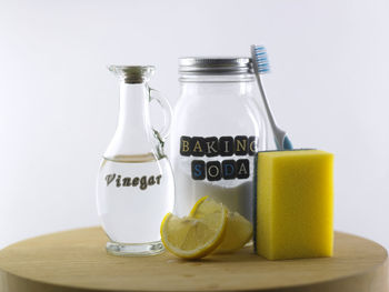 Close-up of baking soda in glass jar vinegar and lemon on table