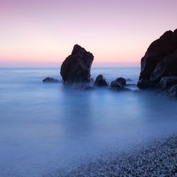 Rocks on sea against sky during sunset