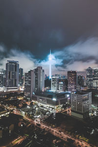 Illuminated cityscape against cloudy sky