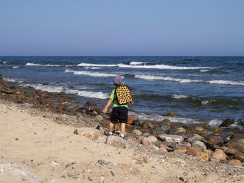 Little boy is throwing stones into the sea