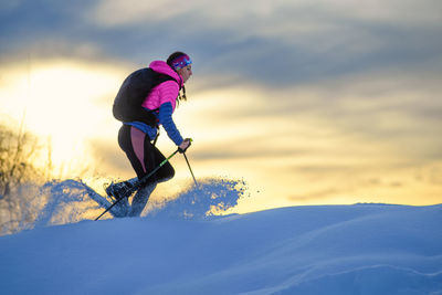 Person in snow against sky during sunset