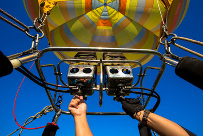 Low angle view of people holding ferris wheel against sky