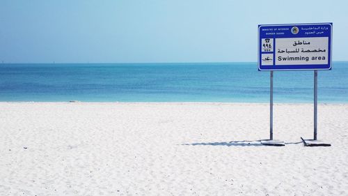 Information sign on beach against sea