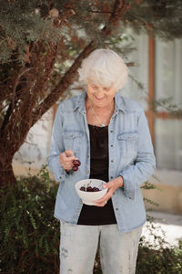 Elderly woman holding a bowl of ripe cherries