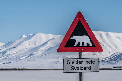 Road sign with polar bear and snow-covered mountains on svalbart.