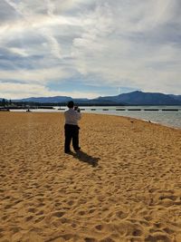 Rear view of man standing on beach against sky