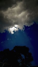 Low angle view of silhouette trees against blue sky