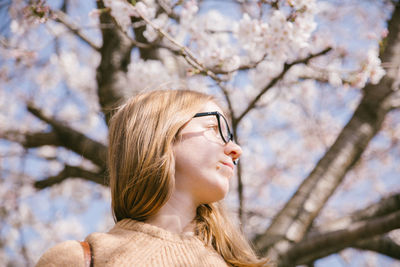 Low angle view of woman against cherry blossom tree