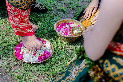 Low section of women standing on pink flower