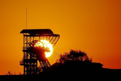 Silhouette built structure against orange sky