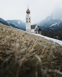 Surface level image of church on mountain against sky during winter