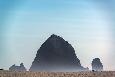 Rock formations on beach against sky