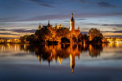 Reflection of building and trees on water at sunset