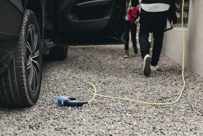 Low section of man with daughter at electric car charging station