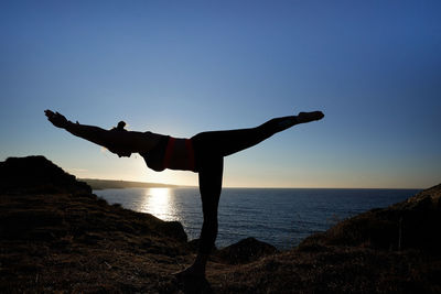 Rear view of woman standing on beach against clear sky