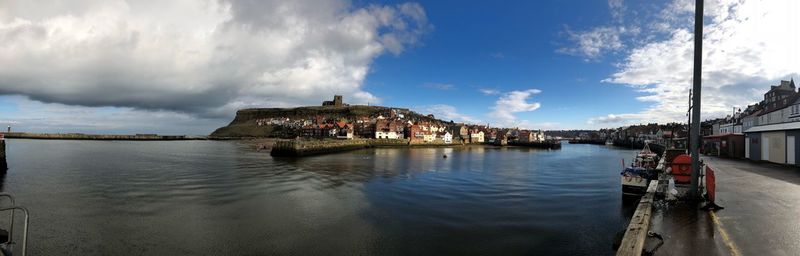 Panoramic view of buildings along with river against sky