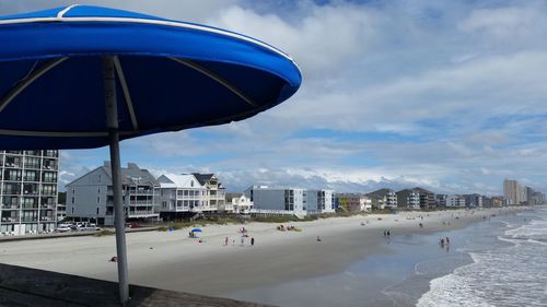 People at beach against sky in city