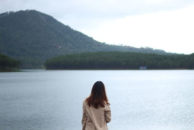 Woman standing by lake against sky