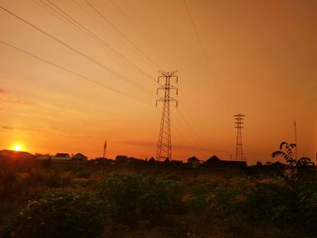 Electricity pylon on field against sky during sunrise