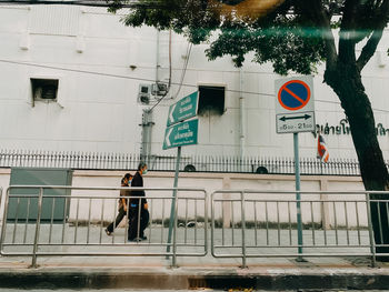 People walking on road sign against building