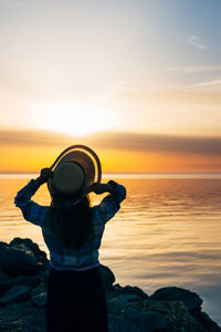 Rear view of man photographing against sky during sunset