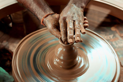 A slow shutter shot of a potter hand making a pot from a pottery wheel at hubli, karnataka, india.