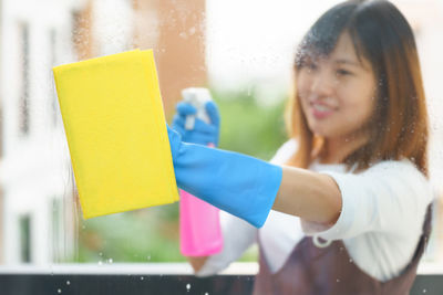 Young woman holding umbrella while standing against curtain