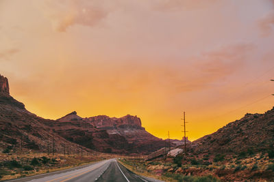 Golden sunset over storm clouds along empty highway in moab, utah.