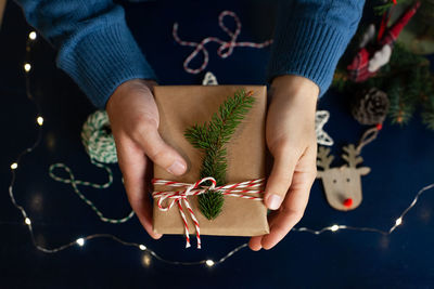 Man wraps a handmade eco style christmas present in kraft paper and natural spruce branches 