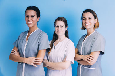 Portrait of smiling doctors with arms crossed standing against wall