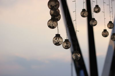 Low angle view of lighting equipment hanging against sky