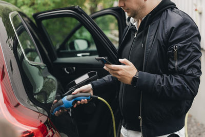 Mid adult man with electric car at charging station