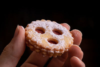 Close-up of hand holding ice cream cone against black background