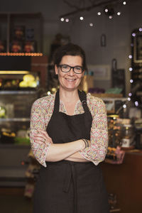 Portrait of confident owner standing with arms crossed at store