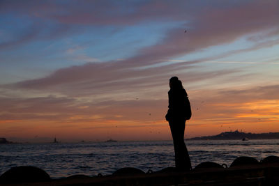 Silhouette man standing on beach against sky during sunset