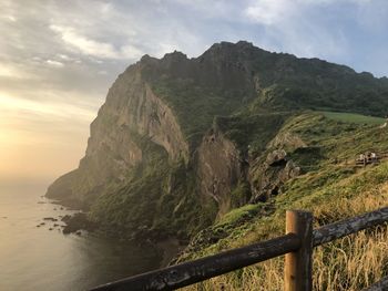 Scenic view of mountain by sea against sky