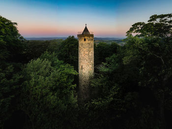 Tower amidst trees and buildings against sky