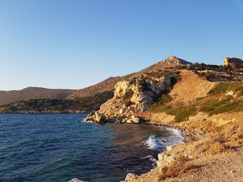 Scenic view of sea and mountains against clear blue sky