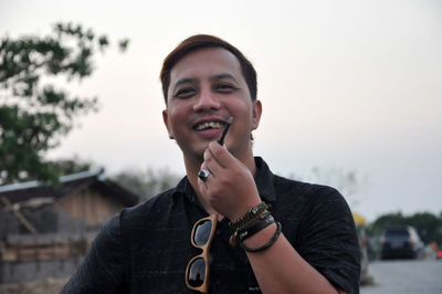 Portrait of smiling man standing against sky