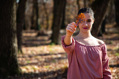 Portrait of young woman holding leaf