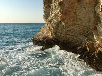 Rock formation in sea against clear sky