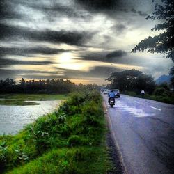 Country road against cloudy sky