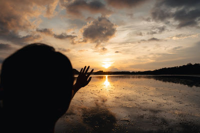 Silhouette woman standing at beach against sky during sunset