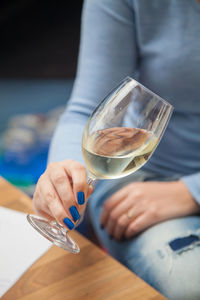 Midsection of woman holding drink on table