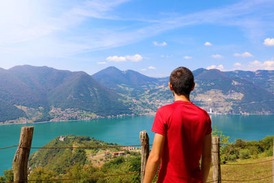 Rear view of man looking at mountains against sky