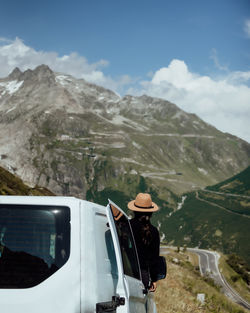 Man in car by mountains against sky