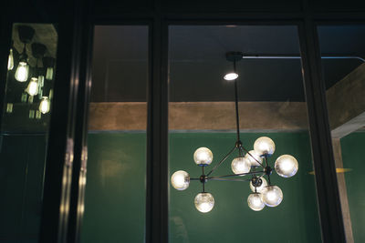 Low angle view of illuminated light bulb hanging from ceiling