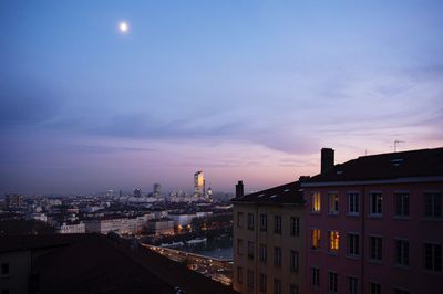 Illuminated buildings against sky at sunset