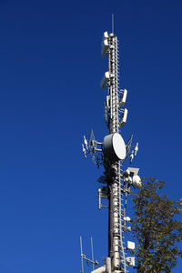 Low angle view of communications tower against clear blue sky