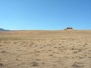 Scenic view of desert against clear blue sky